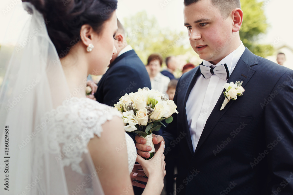 Groom with pink cheeks gives wedding bouquet to beautiful bride Groom with pink cheeks gives wedding bouquet to beautiful bride