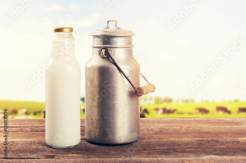 milk can and bottle on table near the cow pasture meadow photo