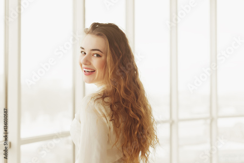 portrait of beautiful young woman with makeup posing by window