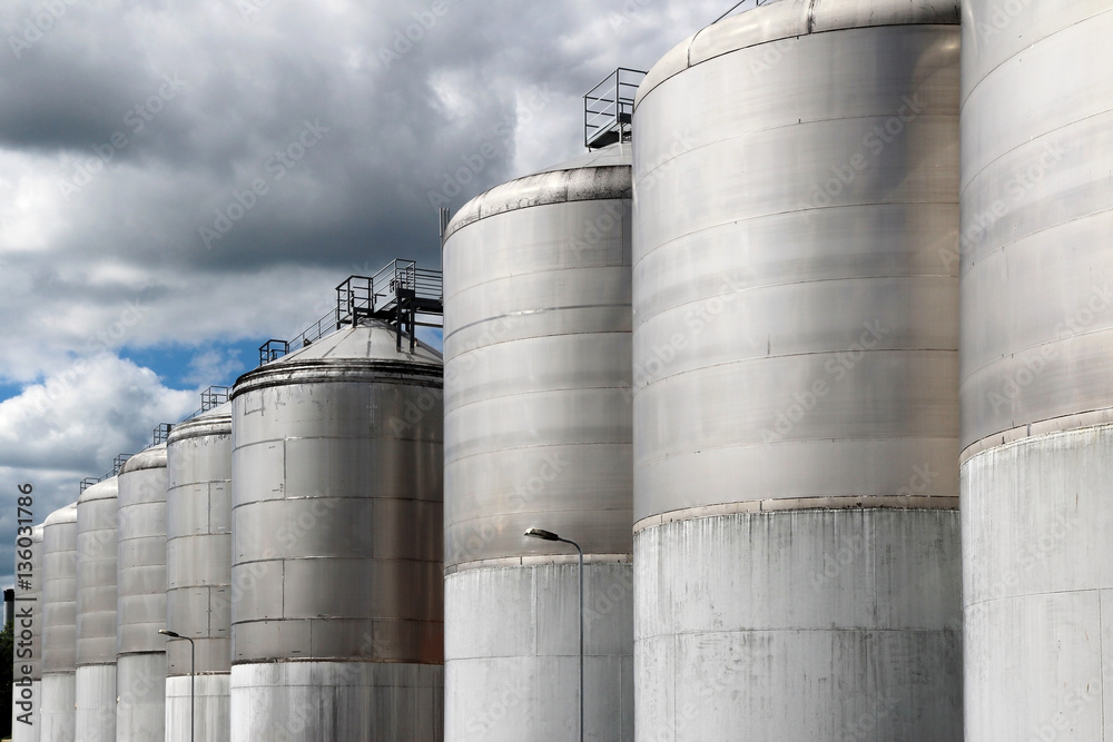 large stainless steel fermentation vessel under cloudy sky