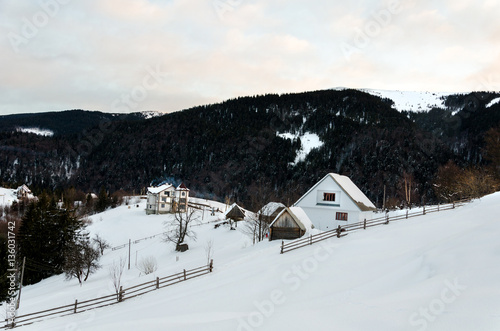House on a hillside covered with snow and green trees on the sid