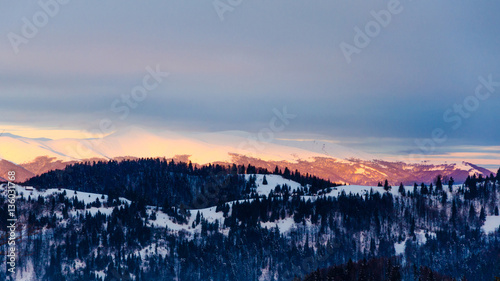 Winter mountain view at dawn, snow top mountains, green trees an