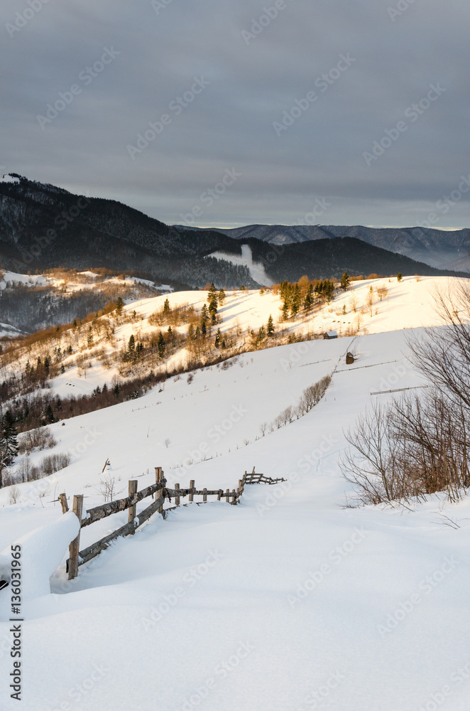 Winter mountain view at dawn wooden fence in snow, blue, green t