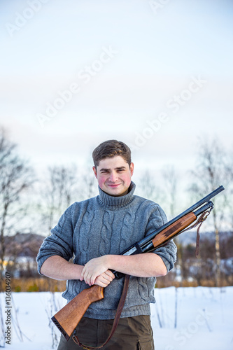 Young handsome man in sweater with hunting rifle