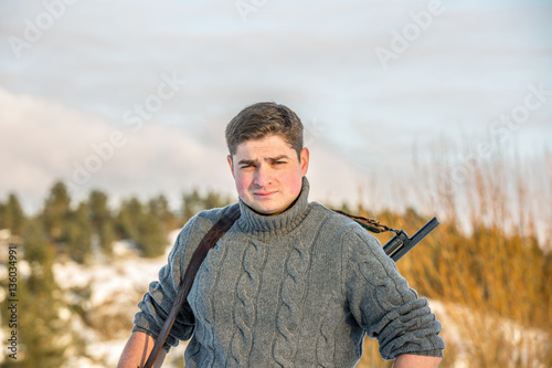 Young handsome man in sweater with hunting rifle photo