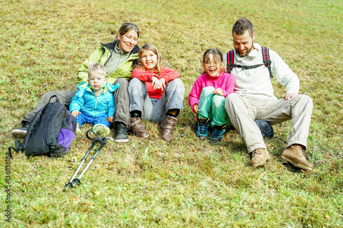 Happy traveler family sitting on grass doing trekking in switzerland