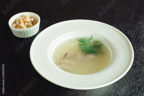 Chicken soup with crackers and dill in a white plate on the table