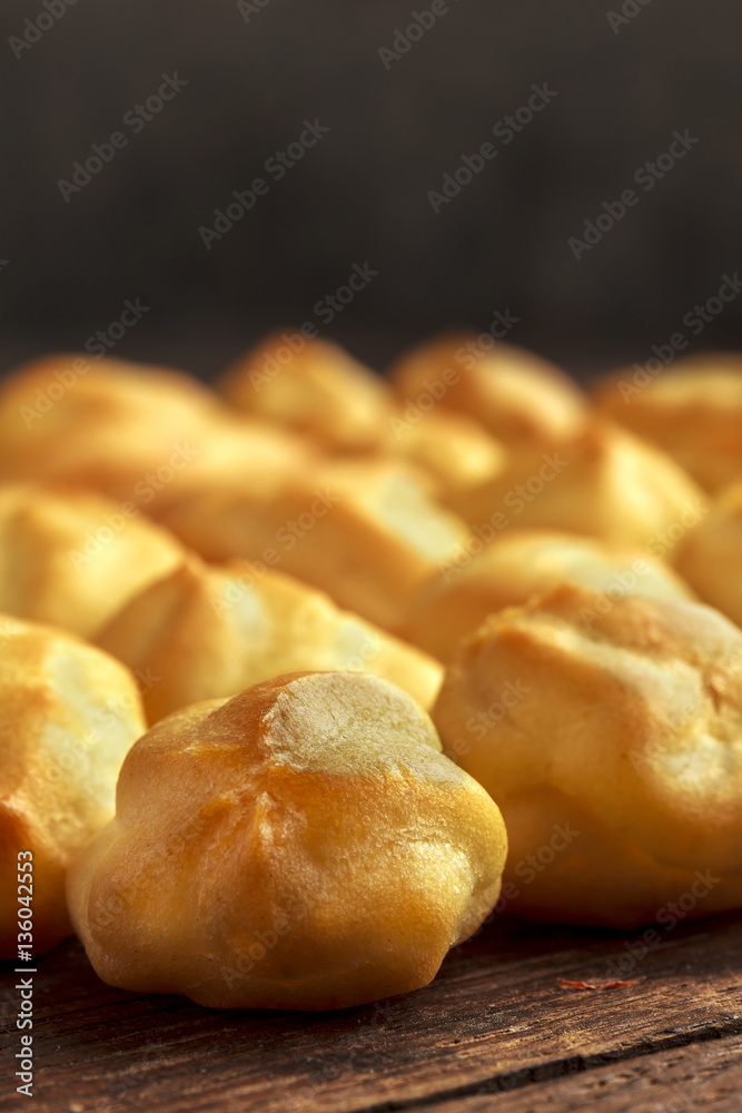 Eclairs or profiterole in blue paper cup on dark background. French dessert. Empty space for design text template.