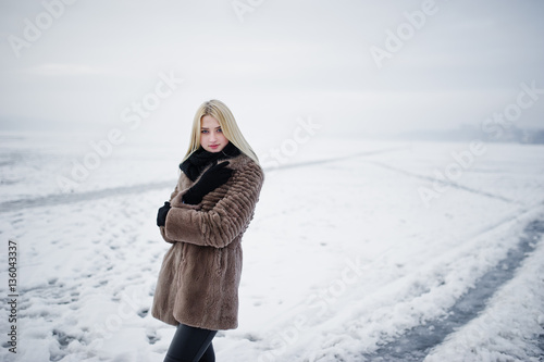 Portrait of young elegance blonde girl in a fur coat background