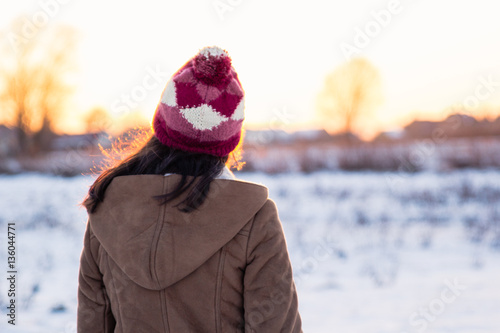 Teenage girl enjoys bright sunset lights in winter