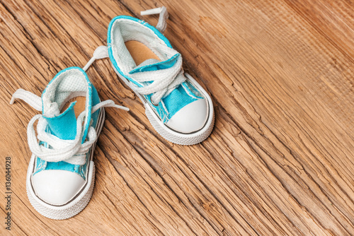 Toy blue sneakers on old wooden surface