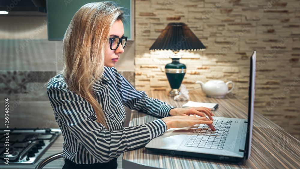 attractive girl in glasses is typing on a laptop