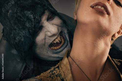 Ancient monster vampire demon bites a woman neck. Halloween fant photo