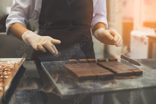 Chef cutting homemade chocolate in kitchen. photo