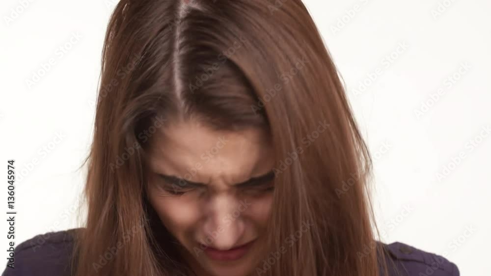 Sad young Caucasian female with long brown hair crying over white background. Close up footage Sad young Caucasian female with long brown hair crying over white background. Close up footage