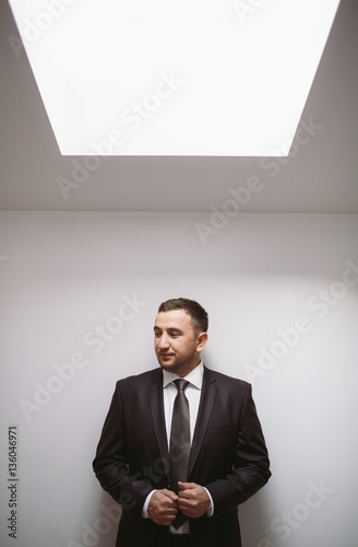 Groom in the luxury black suit in the hotel