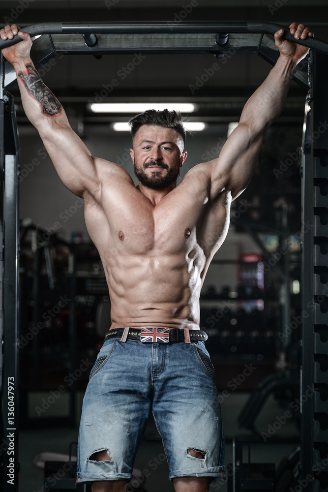 Brutal strong bodybuilder man pumping up muscles and train gym Brutal strong bodybuilder man pumping up muscles and train gym