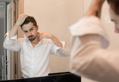 Fotótapéta Portrait of stylish cheerful glad happy handsome cheerful young man combing his hair and laugh