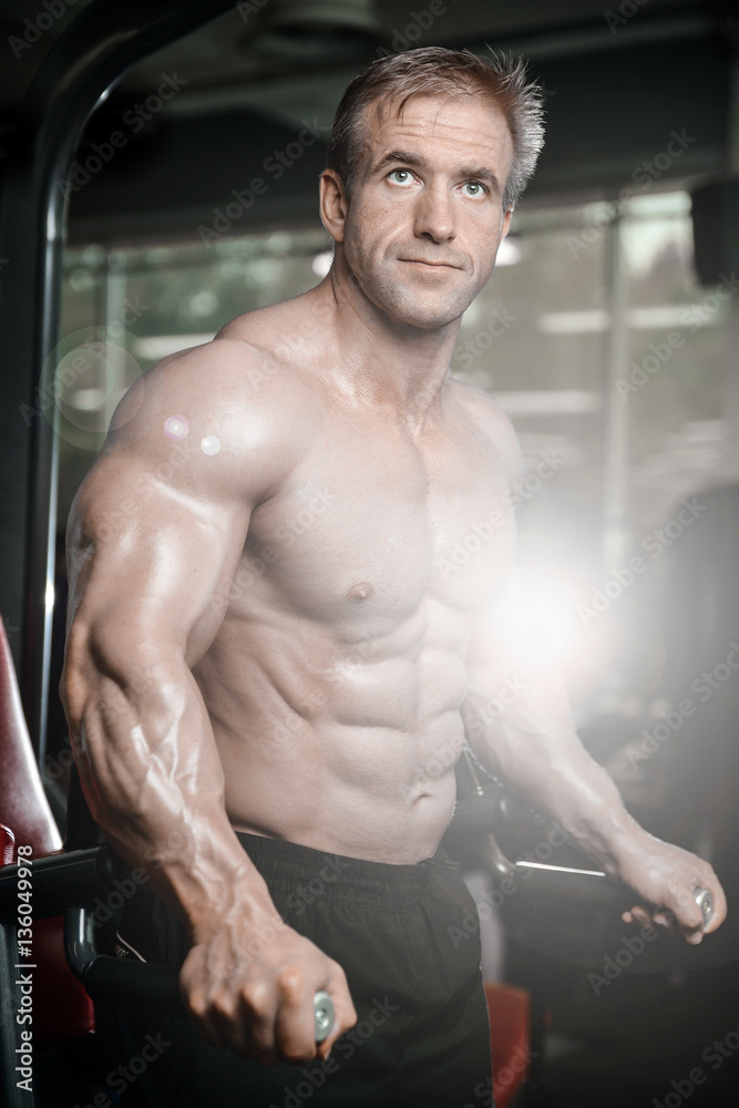 Obraz premium Brutal strong bodybuilder man pumping up muscles and train gym