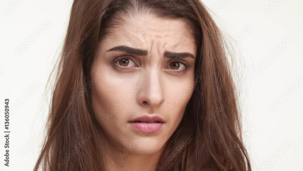 Skeptical beautiful Caucasian female standing on white background looking forward with disappointment in slowmotion. Close up footage Skeptical beautiful Caucasian female standing on white background looking forward with disappointment in slowmotion. Close up footage