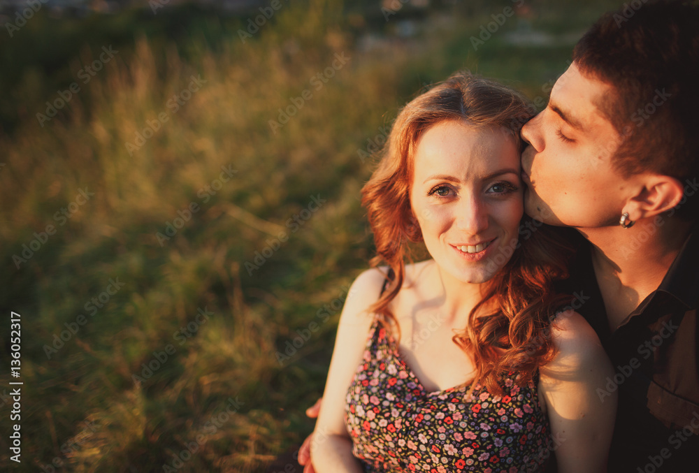 The beautiful couple in love sits on the grass The beautiful couple in love sits on the grass