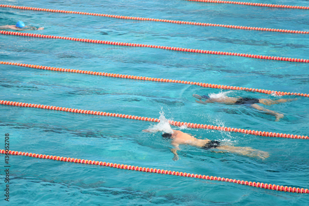 Naklejka premium Healthy young men swimming in а mineral water pool. Male swimmers swimming the front crawl and breaststroke in a pool. Active hobby and leisure.