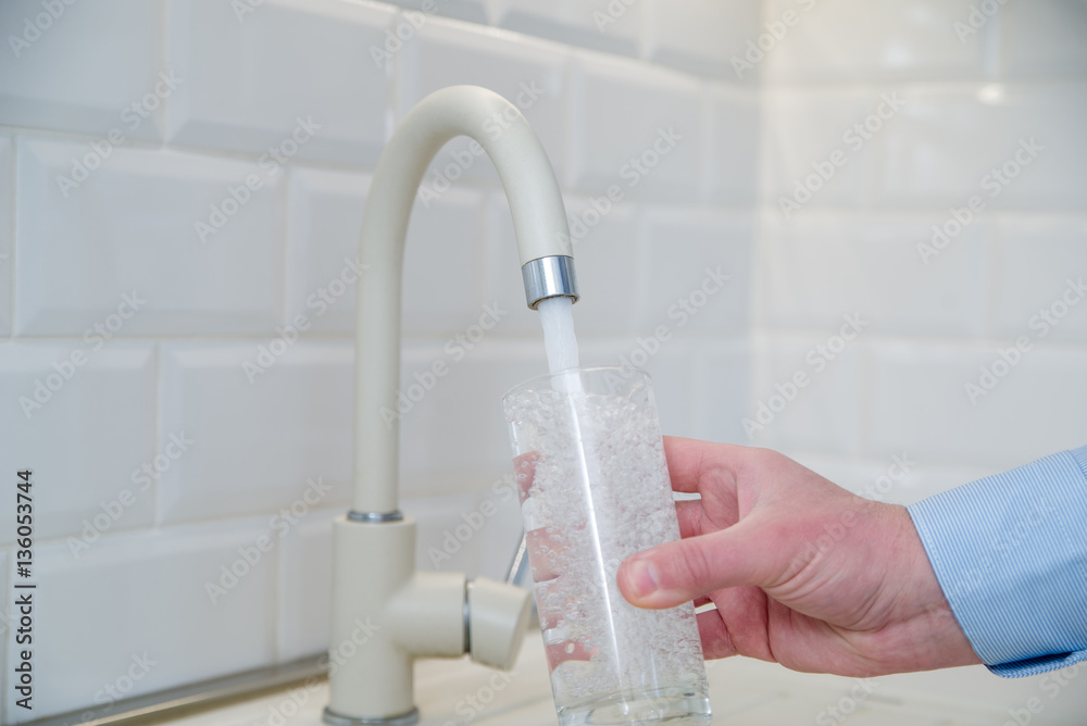 man pours water into a glass from a faucet man pours water into a glass from a faucet