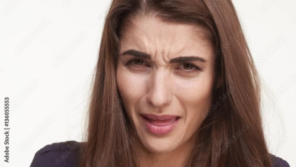 Sad young Caucasian female with long brown hair crying over white background. Close up footage in slowmotion Sad young Caucasian female with long brown hair crying over white background. Close up footage in slowmotion