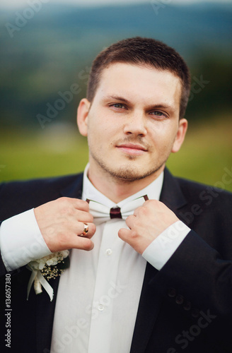 beautiful portrait of handsome and young groom outdoors