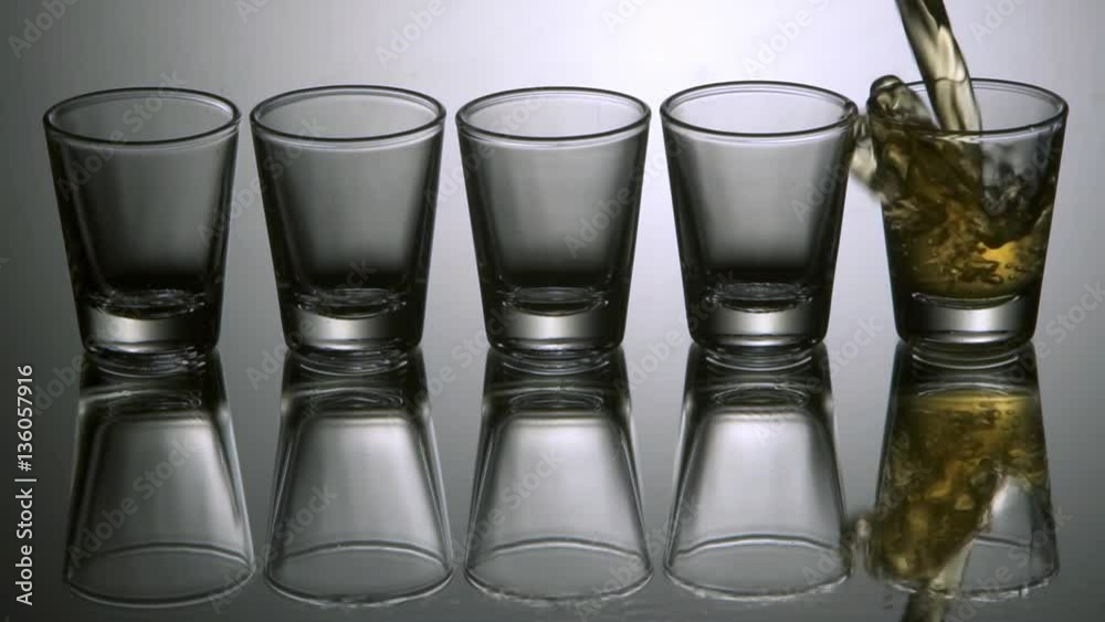 Pouring tequila shots, slow motion.