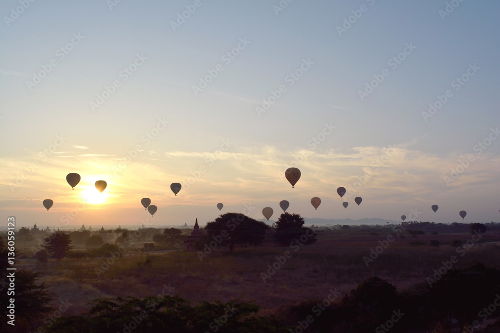 Sunrise with hot air balloons are flying over the pagodas plain of Bagan, Myanmar.