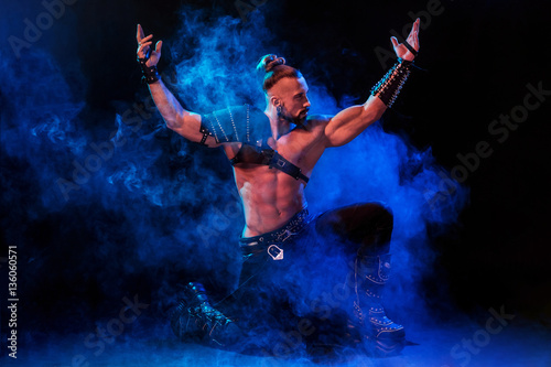 Young and muscular man performing a theatrical pose on stage.