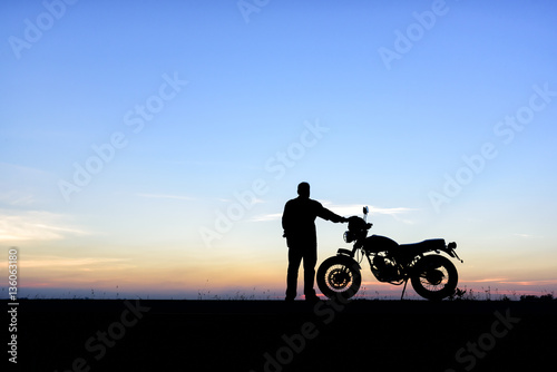 Silhouette of man and a motorcycle with sunset background