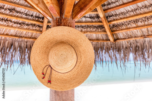 Fototapeta Naklejka Na Ścianę i Meble -  Sun hat hanging on sunshade umbrella on tropical beach. Maldives.