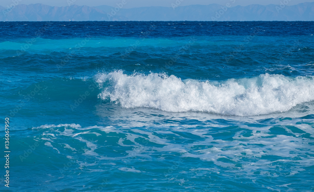 A wave breaks on the beach in the Aegean Sea on the island of Rhodes