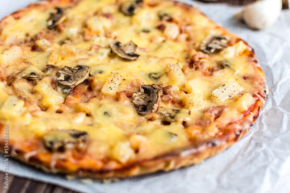 Hawaiian pizza with meat, mushrooms and pineapple on a wooden background Hawaiian pizza with meat, mushrooms and pineapple on a wooden background