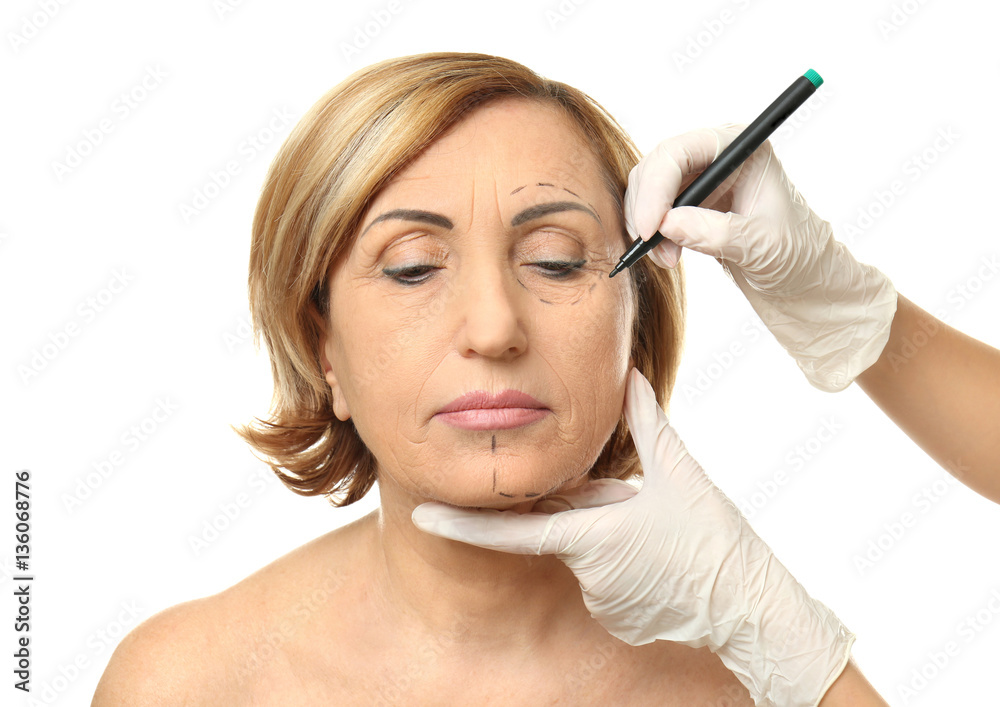 Obraz premium Surgeon hands drawing marks on female face for plastic operation