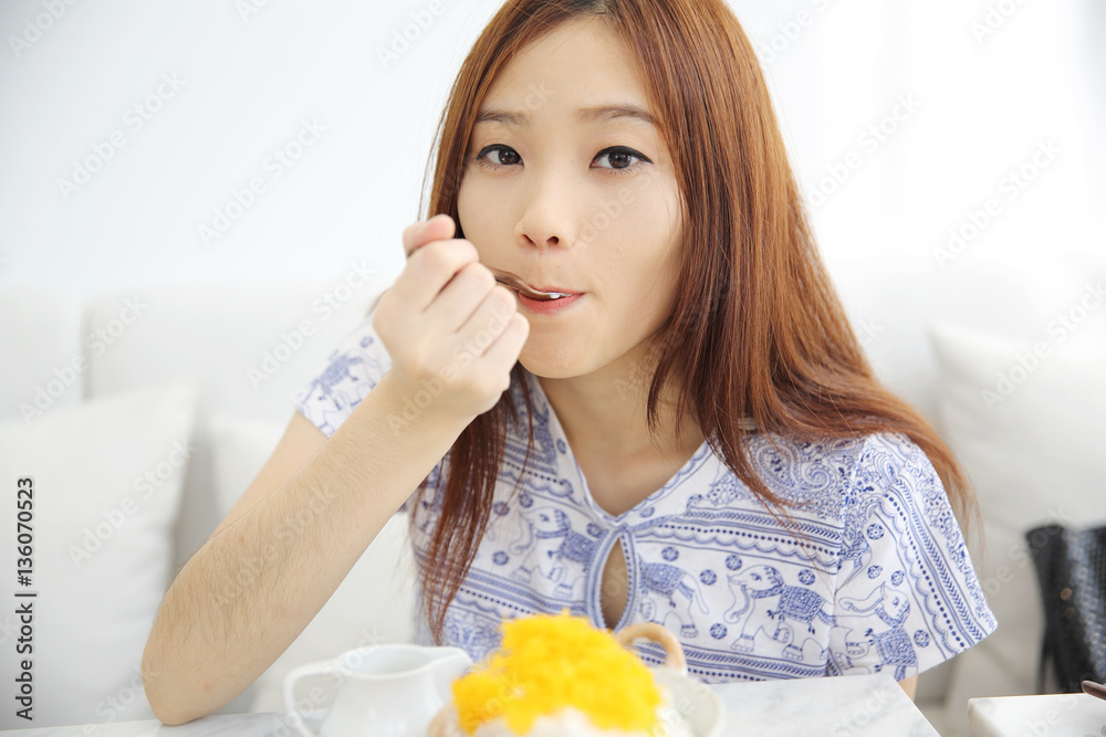 Asian young woman eating Shaved ice with milk and coconut Asian young woman eating Shaved ice with milk and coconut