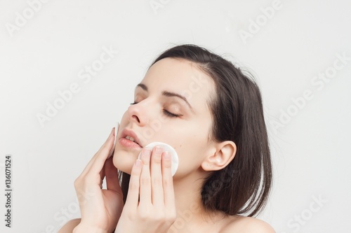 woman wiping her face with cotton pads