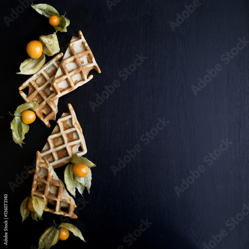waffles and physalis on a black background, blank space on the r