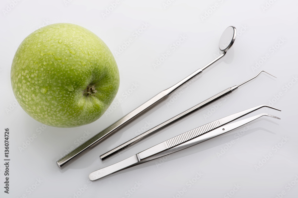 Grüner Apfel mit zahnärztlicher Pinzette Dental Spiegel und Sonde auf  hellem Untergrund – Stock-Foto | Adobe Stock