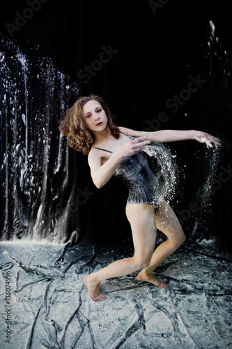 Girl dancer jumping and dancing in the white dust with flour on