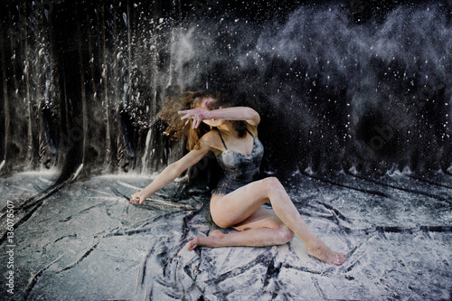 Girl dancer jumping and dancing in the white dust with flour on