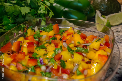 Mango Salsa. Freshly prepared mango salsa in plastic container, in a domestic kitchen with limes and cilantro.