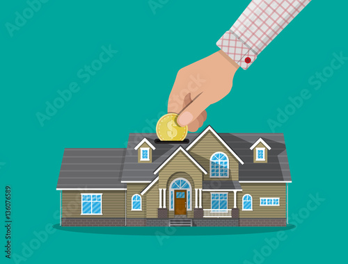 Hand put coin in piggy bank house