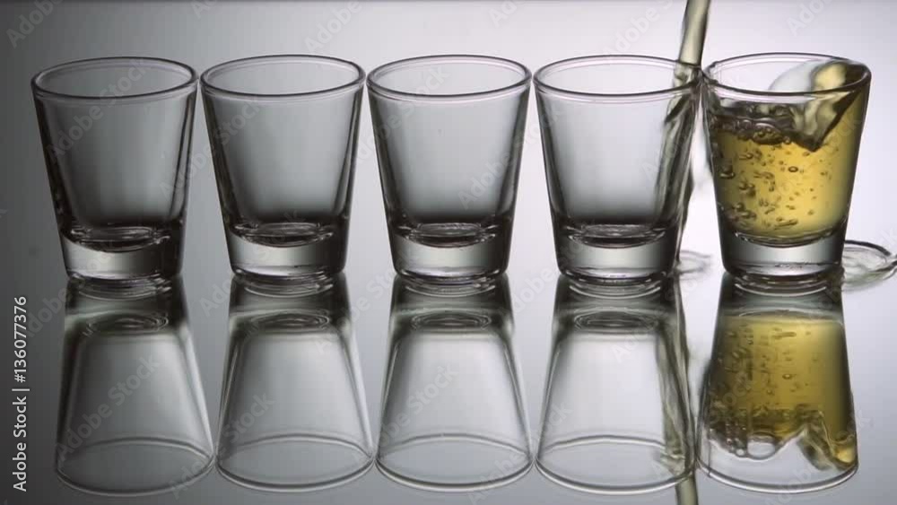 Pouring tequila shots, slow motion.