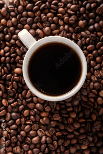 Top view of a cup of hot coffee on coffee beans background