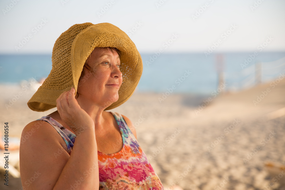 Smiling Senior woman wearing hat at beach