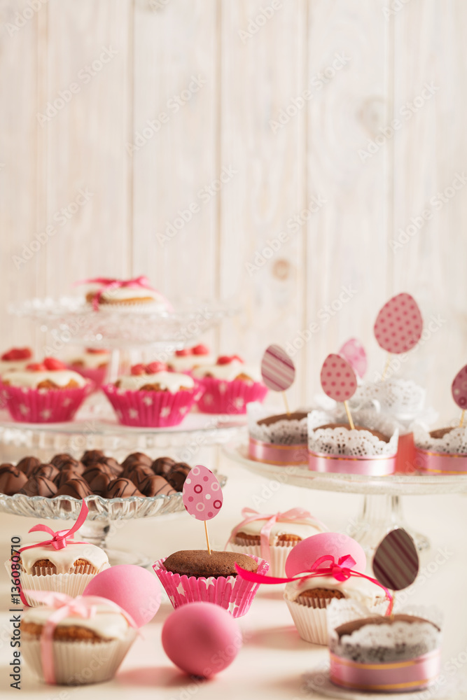 Easter cupcakes decorated with pink candy, paper eggs and ribbon