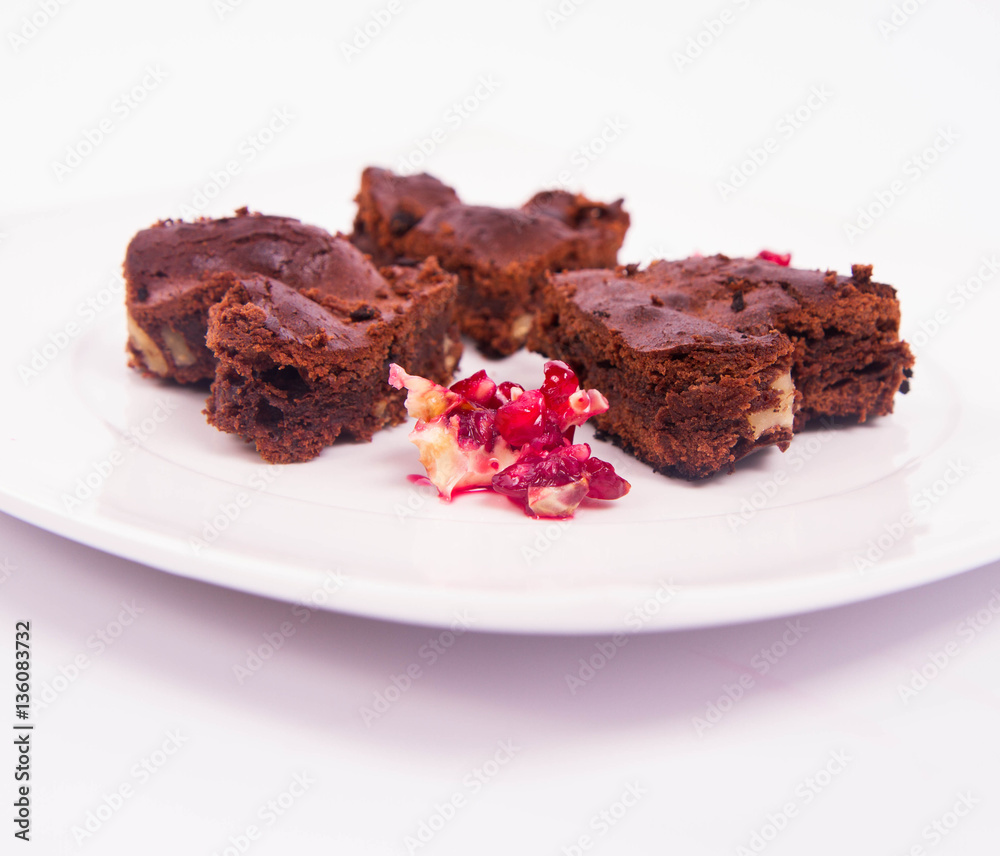 Heart shaped slices of a brownie decorated with pomegranate on white background